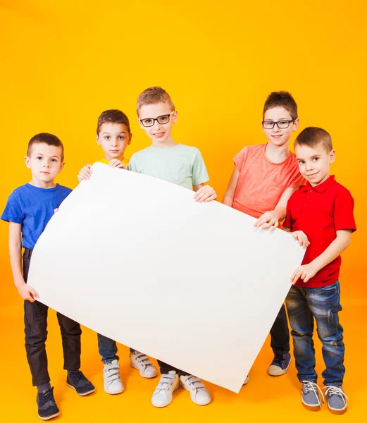 De gelukkige verschillende jongens houden een groot wit papier vast. — Stockfoto