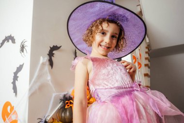 Pembe elbiseli ve cadı şapkalı sevimli kız.
