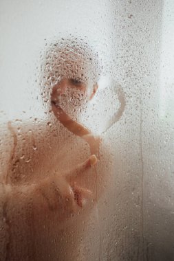 Yoğunlaştırılmış cam kapıya kalp çizen neşeli kadın