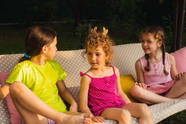 Neşeli kız kardeş salıncakta yatıyor, sarılıyor.