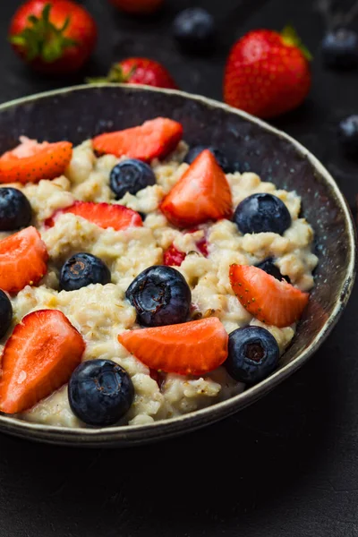 The concept of a healthy breakfast of oatmeal with strawberries and blueberries — Stock Photo, Image