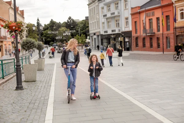 A mãe e a filha se divertem montando scooters — Fotografia de Stock