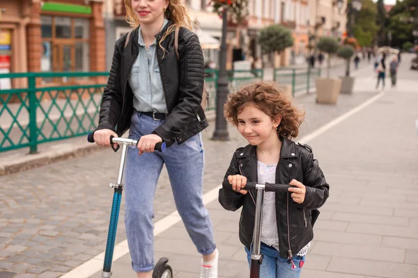 De moeder en dochter hebben plezier rijden scooters — Stockfoto