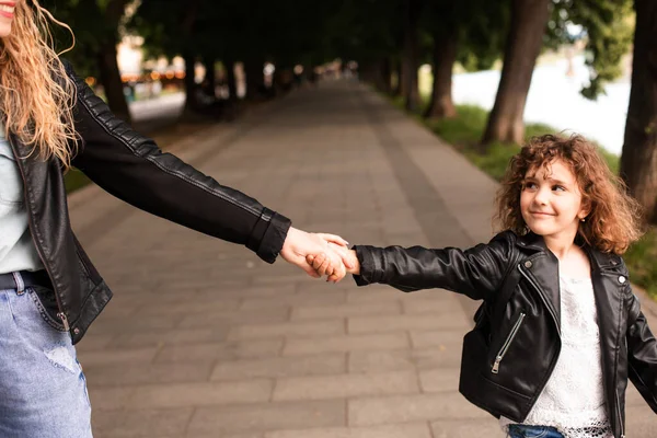 De moeder en het meisje lopen rond in de stad en houden elkaars hand vast. — Stockfoto