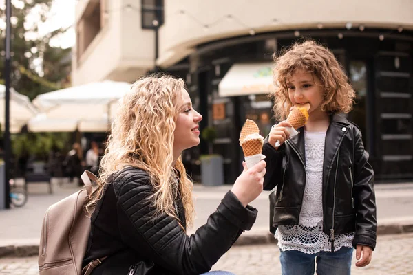 La mère et la fille heureuses tiennent la crème glacée tout en marchant — Photo