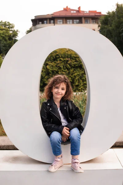 Den lilla flickan sitter i det stora brevet i staden — Stockfoto