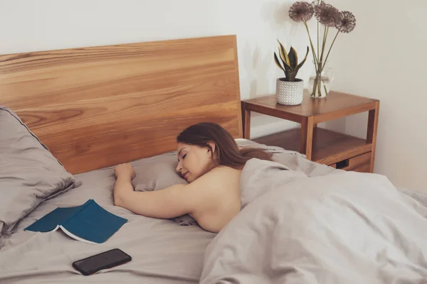 ベッドで読書をしている間、女は眠っていた — ストック写真
