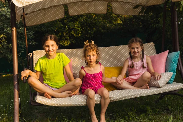 Tre belle sorelle su un'altalena morbida giardino — Foto Stock