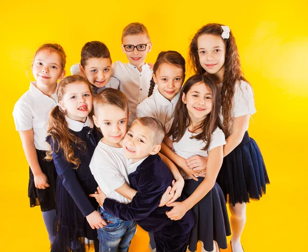 De vänliga klasskamraterna kramas på en gul bakgrund — Stockfoto