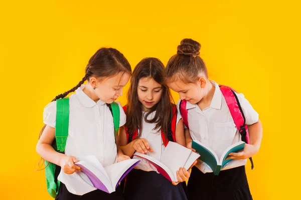 Las colegialas están leyendo los libros en el fondo amarillo — Foto de Stock