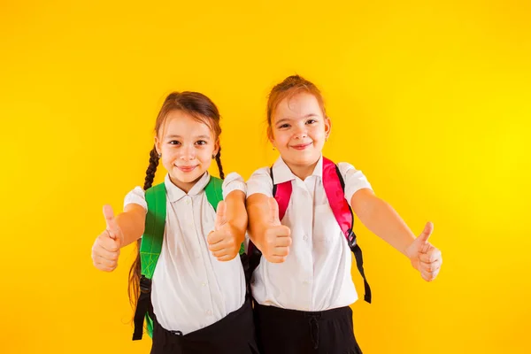 Twee lachende schoolmeisjes van een lagere school duimen omhoog — Stockfoto