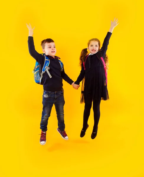 De två klasskamraterna hoppar och håller varandra i handen — Stockfoto