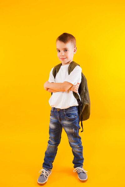 the little pupil wearing style clothes stands with folded arms