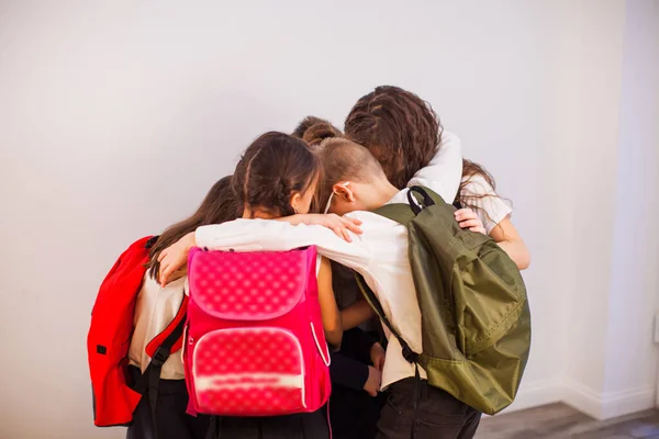 A boldog iskolás gyerekek készen állnak az oktatásra. Iskolás gyerekek egyenruhában, hátizsákkal az osztályban. — Stock Fotó