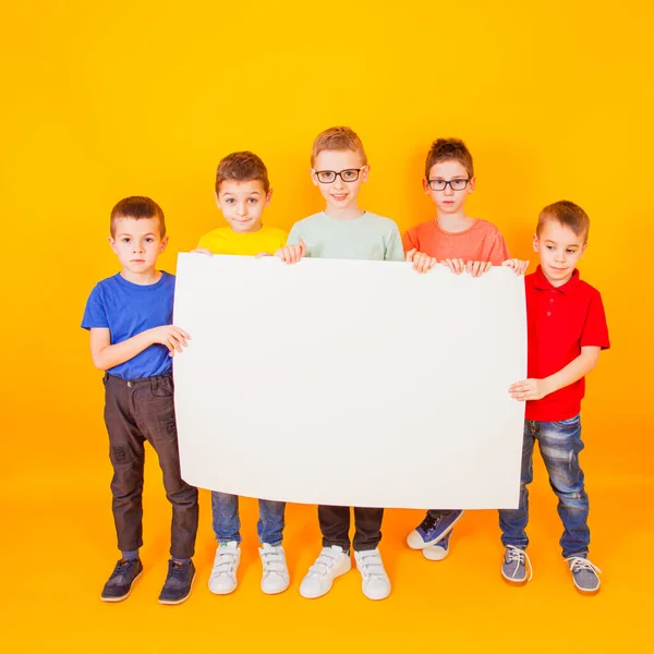 Die verschiedenen kleinen Jungen halten ein großes weißes Papier in der Hand — Stockfoto