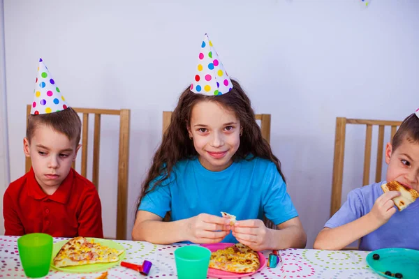 De kleine kinderen eten pizza op het verjaardagsfeestje. — Stockfoto