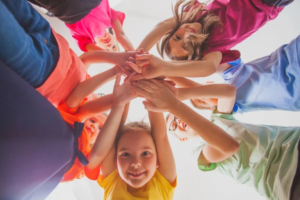Equipo de niños y niñas están apilando las manos juntos — Foto de Stock