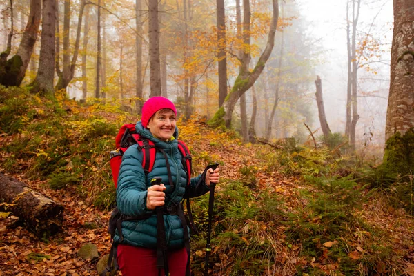 Mutlu kadın yürüyüşçü güzel sonbahar ormanında yürüyor. — Stok fotoğraf