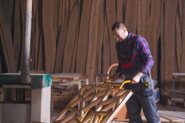 Tahta dekoratif elementleri el arabası kullanarak taşıyan bir adam.