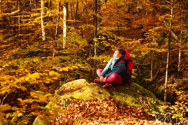 Γυναίκα ταξιδιώτη στο δάσος φθινόπωρο κάθεται στην πέτρα — Φωτογραφία Αρχείου