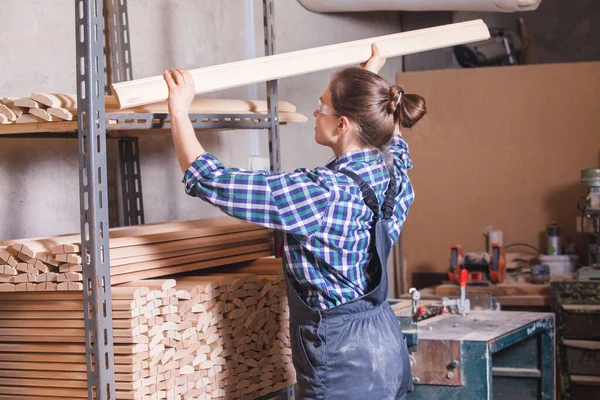 Aprendiz comprobando tablón de madera en taller de carpintería — Foto de Stock