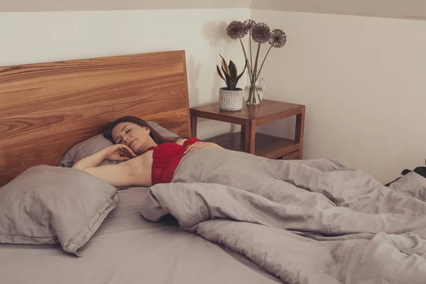 Mladý dospělý dívka skrývající se v posteli pod dekou — Stock fotografie