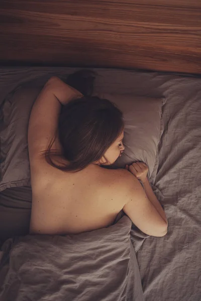 Naakte vrouw slapen in het bed met de hand onder het kussen — Stockfoto