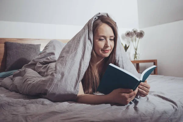 Lovely woman reading, laying on comfortable bed — Stock Photo, Image
