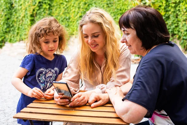 Three generations of women sitting at outdoor cafe terrace — Stock Photo, Image