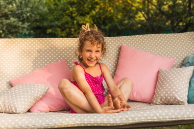 Küçük melek kız gülümsüyor, neşeyle kameraya bakıyor.