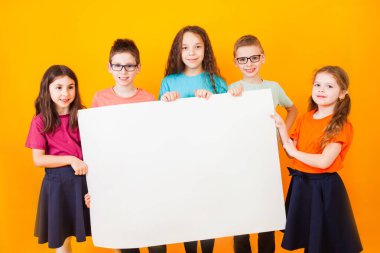 Farklı küçük çocuklar büyük beyaz bir kağıt tutuyorlar.