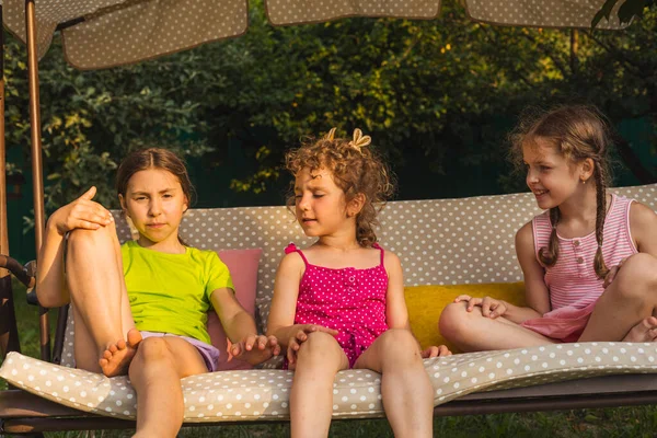 Tres hermanas encantadoras en columpio jardín suave — Foto de Stock