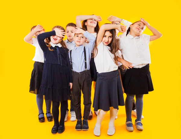 背着背包和双手交叉站在黄色背景上的学童 — 图库照片