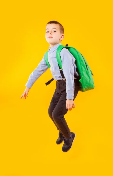 Springen emotionele schooljongen op de gele achtergrond — Stockfoto