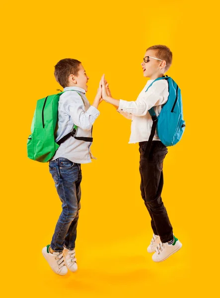 Springende emotionale Schüler auf gelbem Hintergrund — Stockfoto