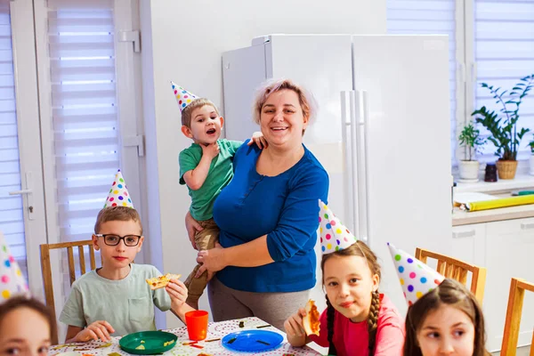 Alegre madre sosteniendo lindo chico en fiesta de cumpleaños — Foto de Stock