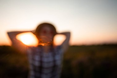 Gün batımında gökyüzünde genç bir kızın bulanık görüntüsü.