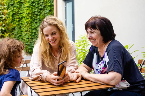 Three generations of women sitting at outdoor cafe terrace — Stock Photo, Image