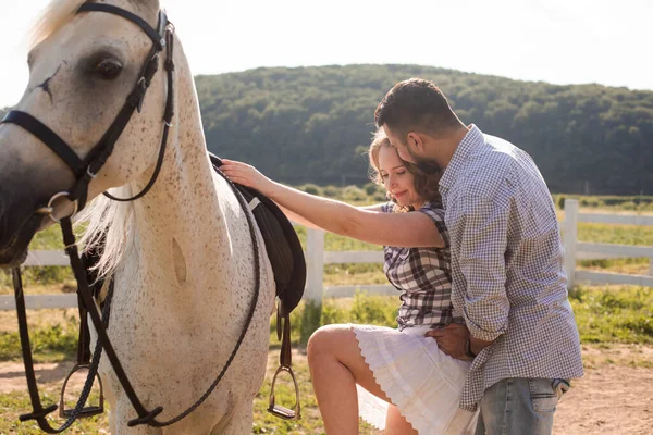 Der junge Mann hilft seiner Frau aufs Pferd — Stockfoto