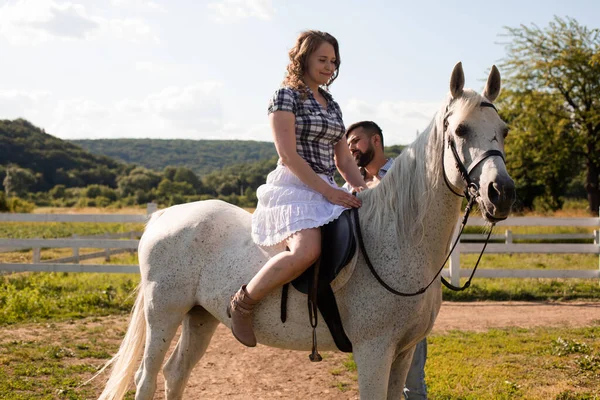 Ο άντρας μαθαίνει σε μια γυναίκα να ιππεύει ένα άλογο. — Φωτογραφία Αρχείου