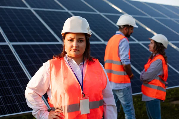 Серьезная женщина-инженер стоит на фоне солнечных батарей — стоковое фото