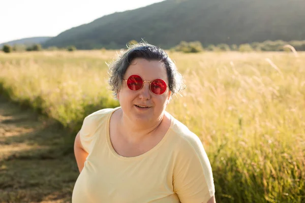 Die fröhliche junge Frau mit Sonnenbrille genießt die Natur — Stockfoto