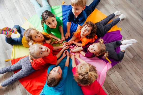 Glückliche Kinder liegen im Kreis auf dem Boden — Stockfoto