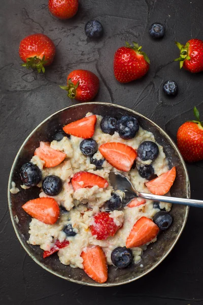 The concept of a healthy breakfast of oatmeal with strawberries and blueberries — Stock Photo, Image