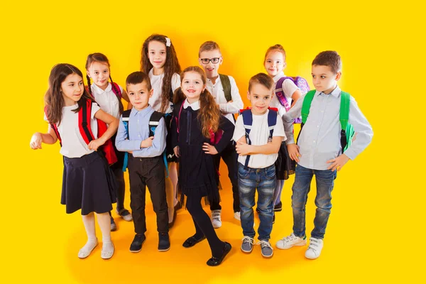 De vriendelijke klasgenoten knuffelen op een gele achtergrond — Stockfoto