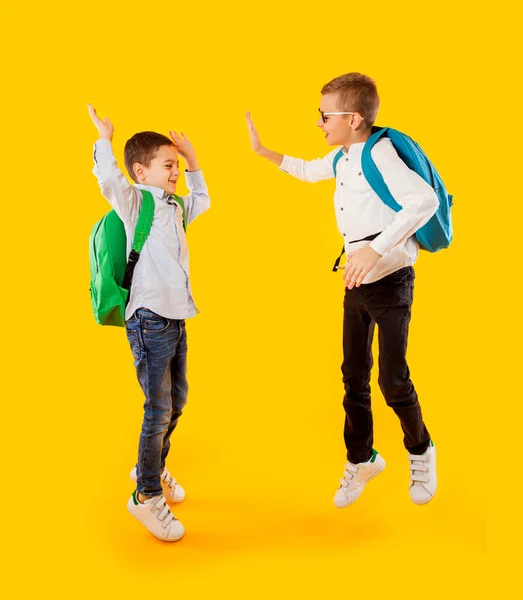 黄色の背景に感情的な学童をジャンプ — ストック写真
