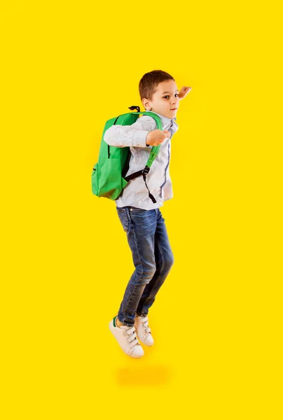 Springen emotionele schooljongen op de gele achtergrond — Stockfoto