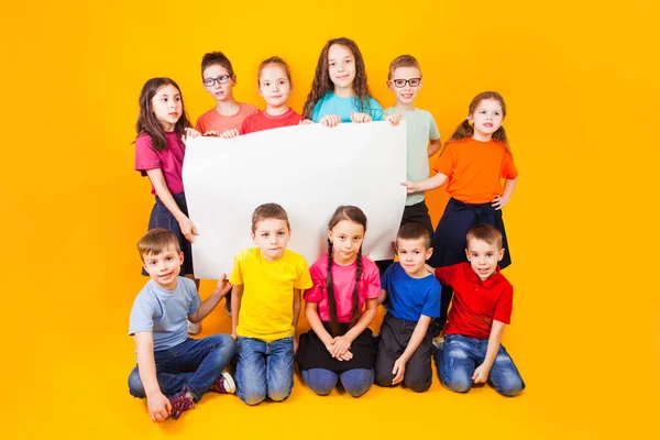 Die Gruppe von Kindern hält ein großes weißes Kopierraum-Plakat in der Hand — Stockfoto