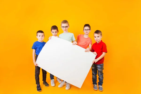 A különböző kisfiúk egy nagy fehér papírt tartanak. — Stock Fotó