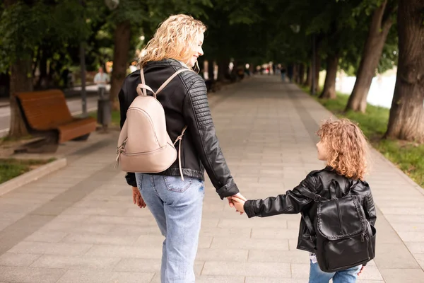 De moeder en het meisje lopen rond in de stad en houden elkaars hand vast. — Stockfoto